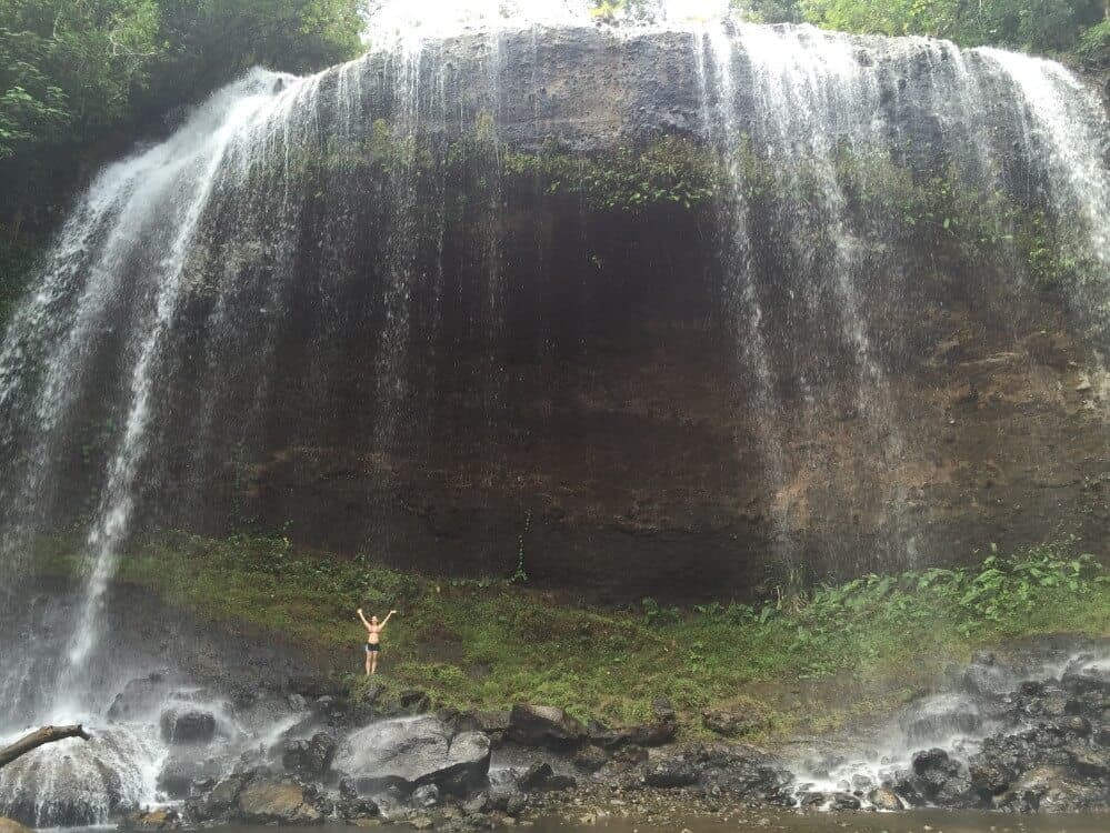 woman standing under Ngardmau waterfall in Palau