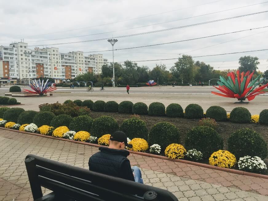 Tiraspol streets with man on a bench and Transnistrian and Russian flags in background