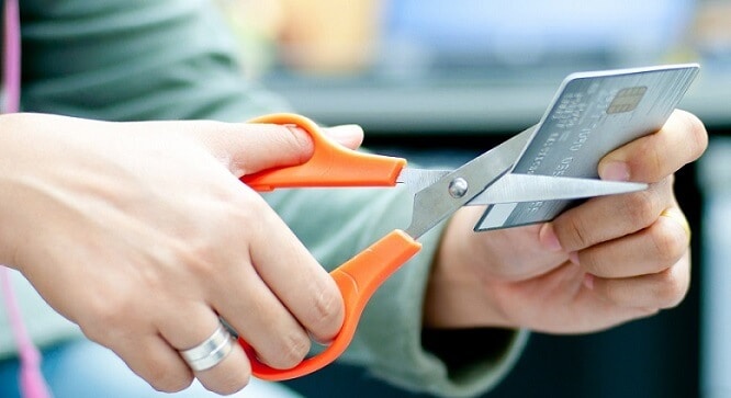 person with scissors cutting up credit card - how to fly for free