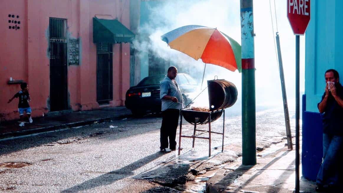 man barbquing under umbrella