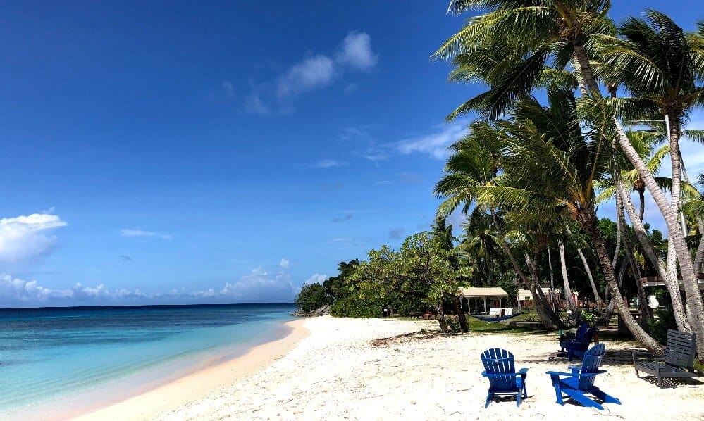 white sand beach with two blue chairs and palm trees on Kwajalein