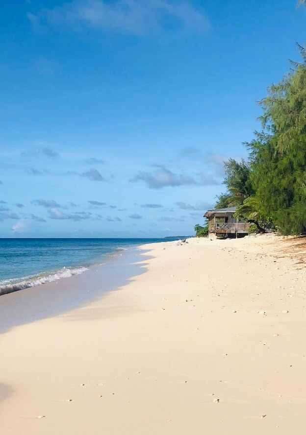 sandy beach with house by ocean on Ebeye island with blue sky