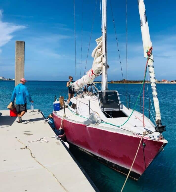 red sailboat in Kwajalein harbor with man and woman loading supplies
