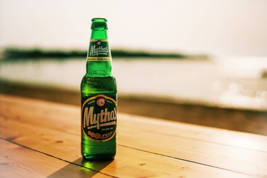 green mythos beer bottle on table with blurry background