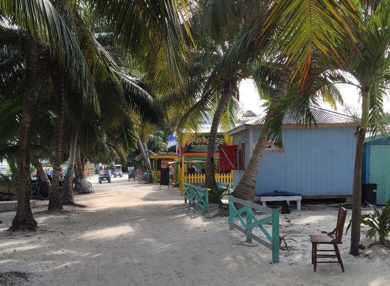 zandpad door blauwe huizen en palmbomen