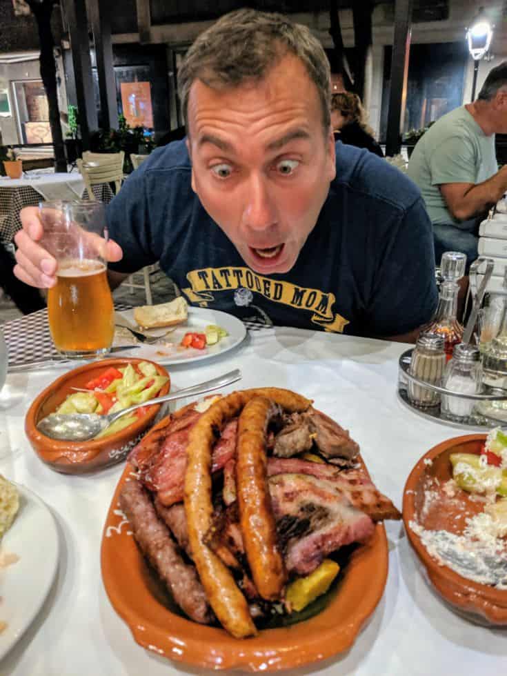 man staring at huge plate of sausages and meat