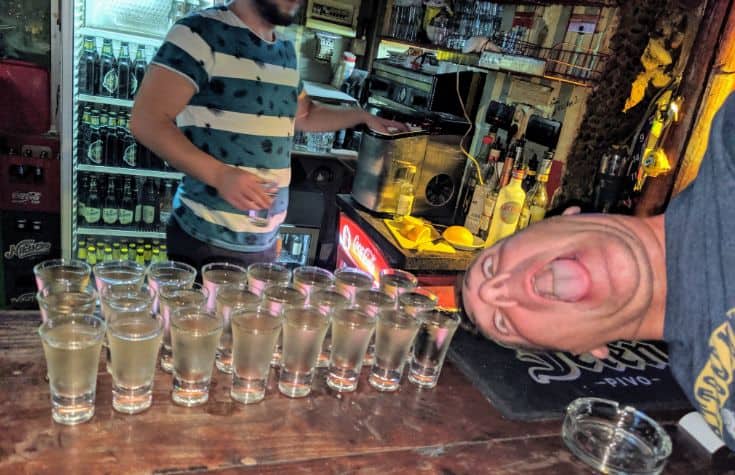 man's head next to 24 shots of rakija on a bar