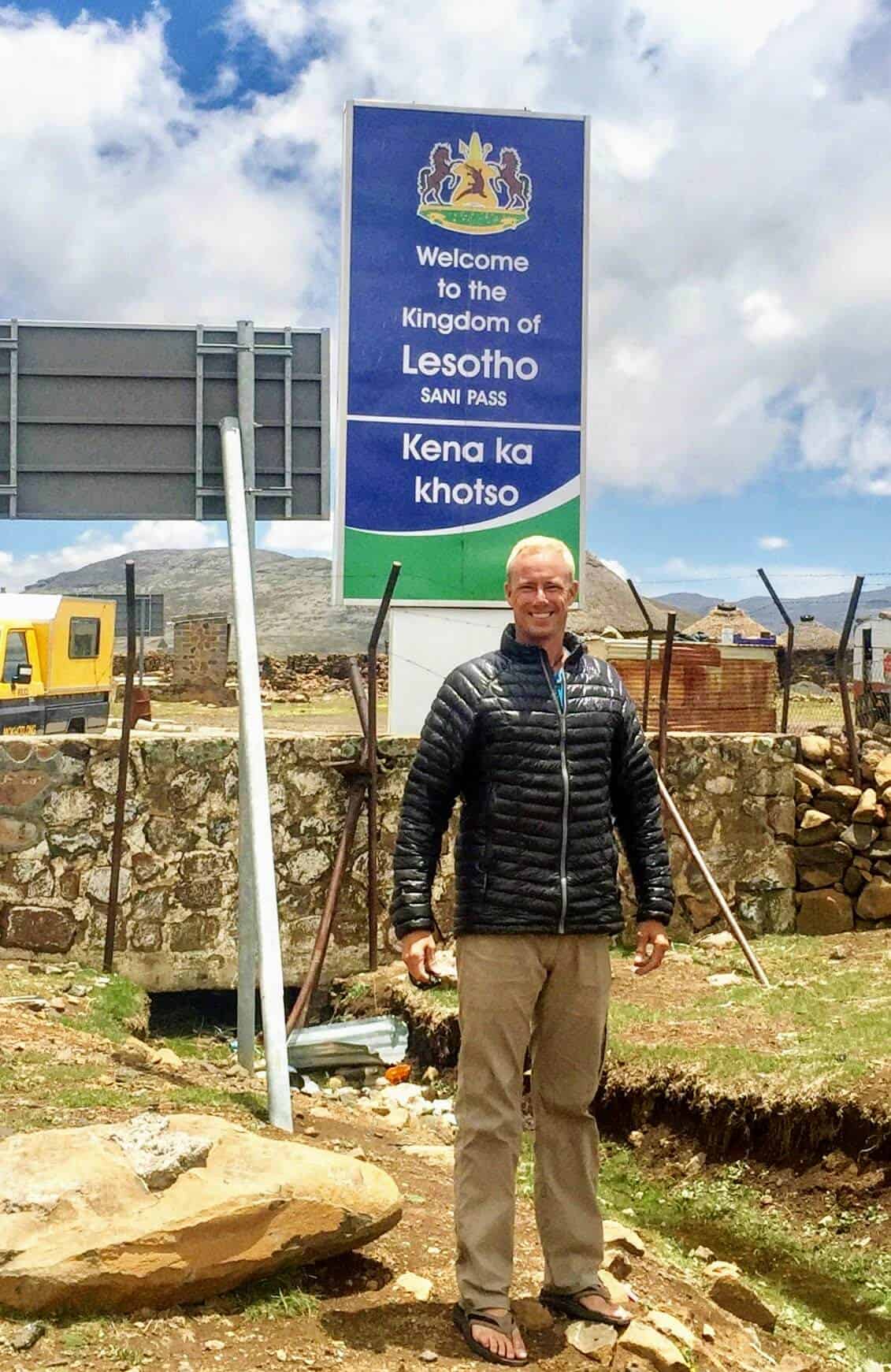 top of Sani Pass Lesotho border sign with man standing in black jacket