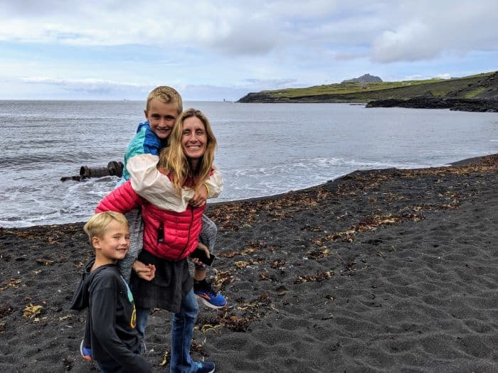 woman and two boys on black sand beach